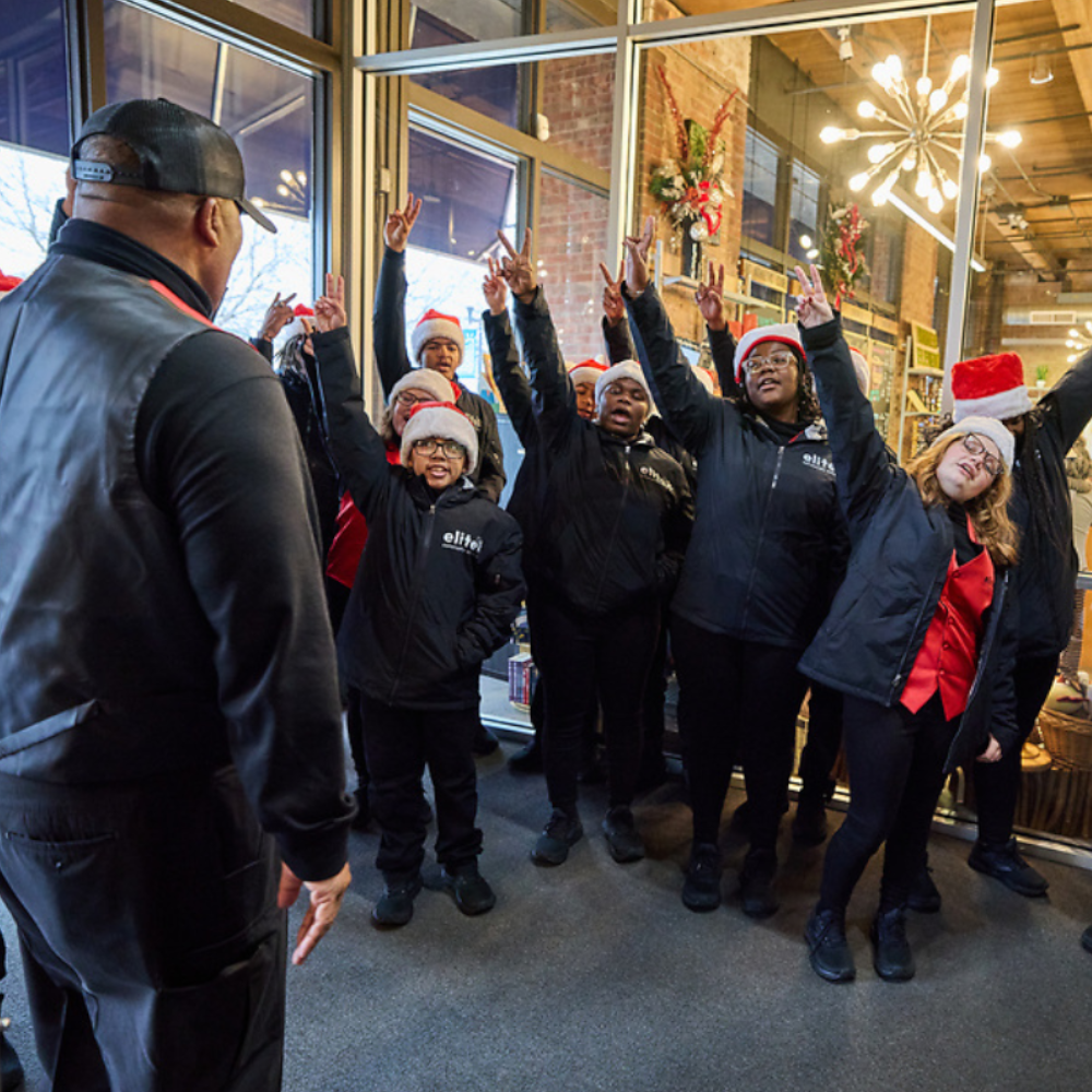 The Elite Christmas Choir gets rallied up to sing by Carl Cannon at the Chocolate Turkey race/walk event.