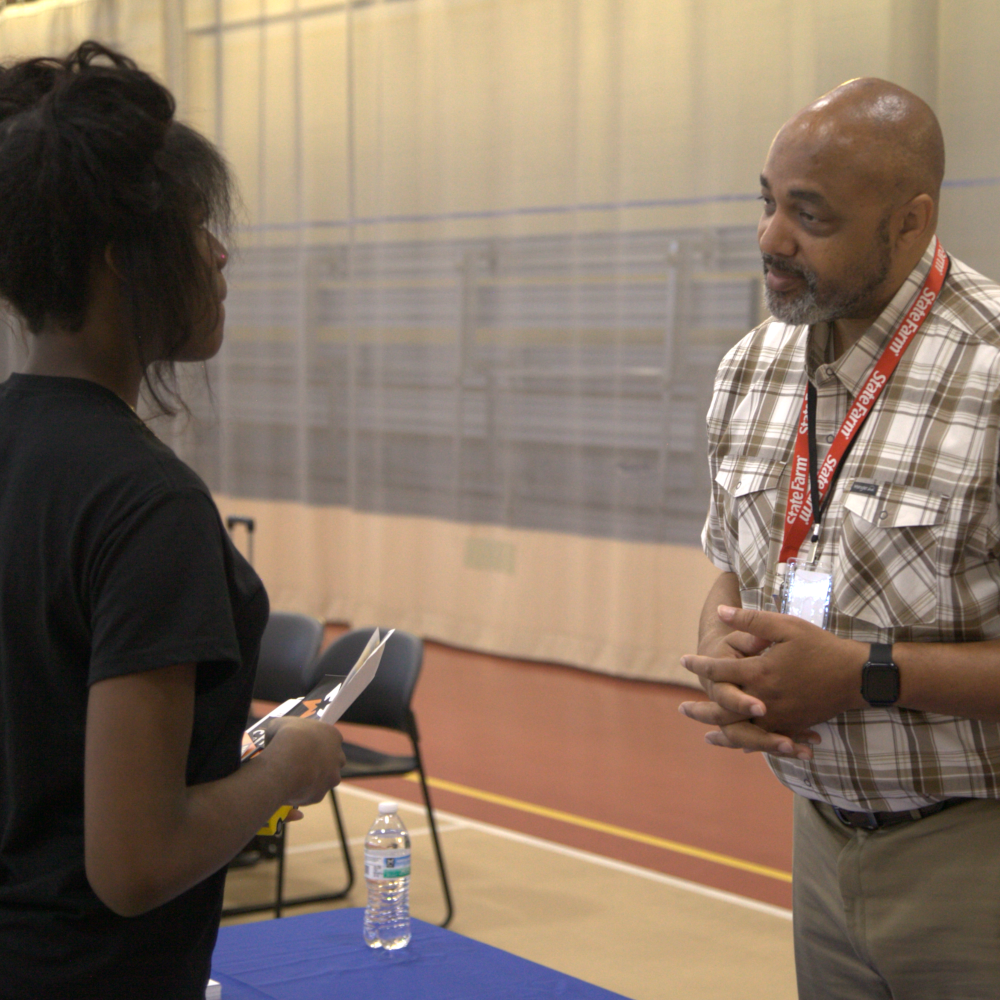 A student receives information from a representative from the Illinois Department of Employment Security at the Elite Community Outreach job fair.