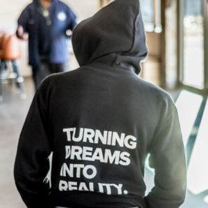 Image of a person wearing a hoodie with the following saying on the backTurning Dreams into Reality